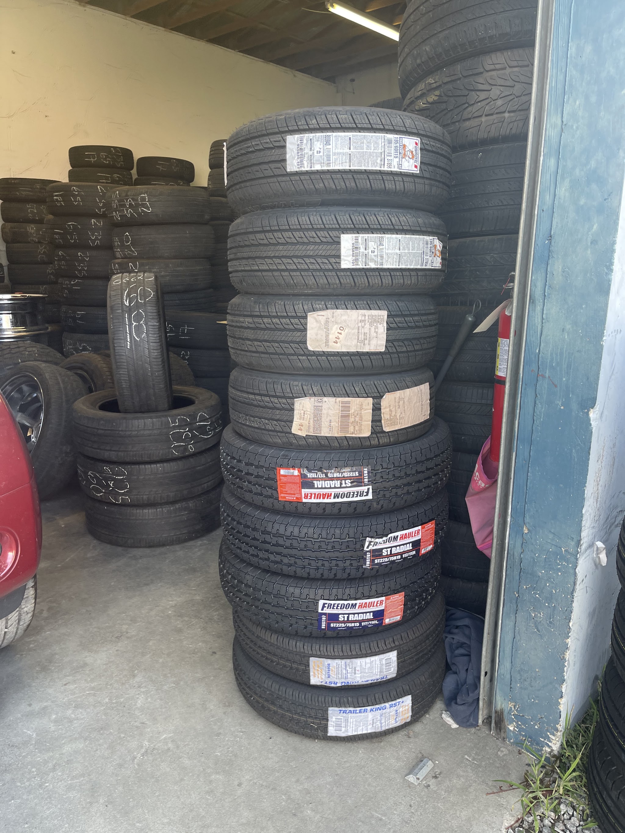 A stack of new tires, with trailer tires on the shelf